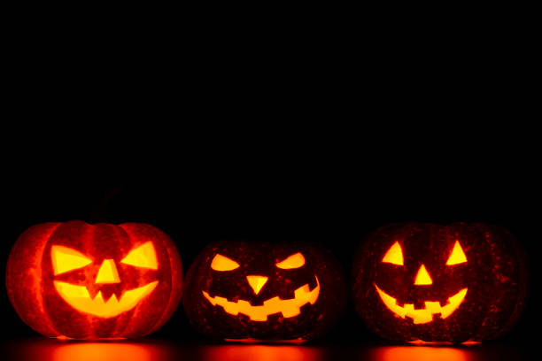 istock Three spooky carved pumpkins on table in darkness 838740222