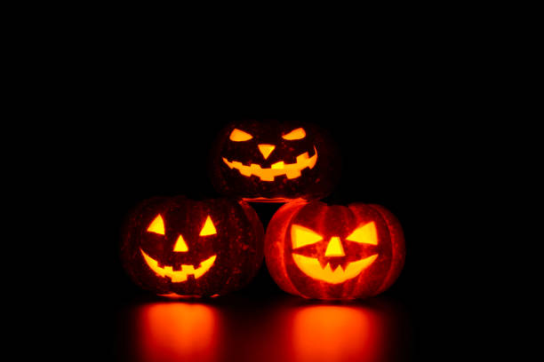 istock Three spooky carved pumpkins on table in darkness 838740236