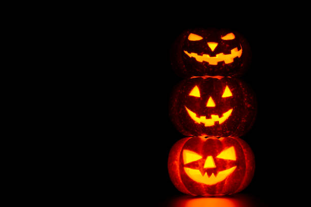 istock Three spooky carved pumpkins on table in darkness 838740280