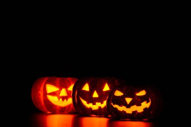 istock Three spooky carved pumpkins on table in darkness 838740366