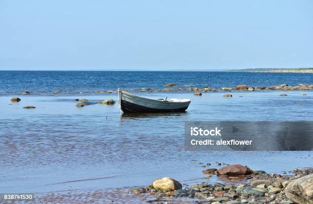 A Wooden Fishing Boat Stands In The Water On A Stony Sea Shoal At Low Tide Near The Shore Stock Photo - Download Image Now