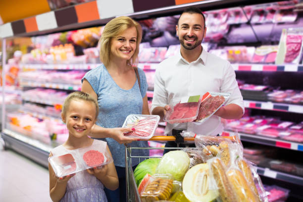 istock parents with daughter choosing meat in refrigerated section in hypermarket 838795406