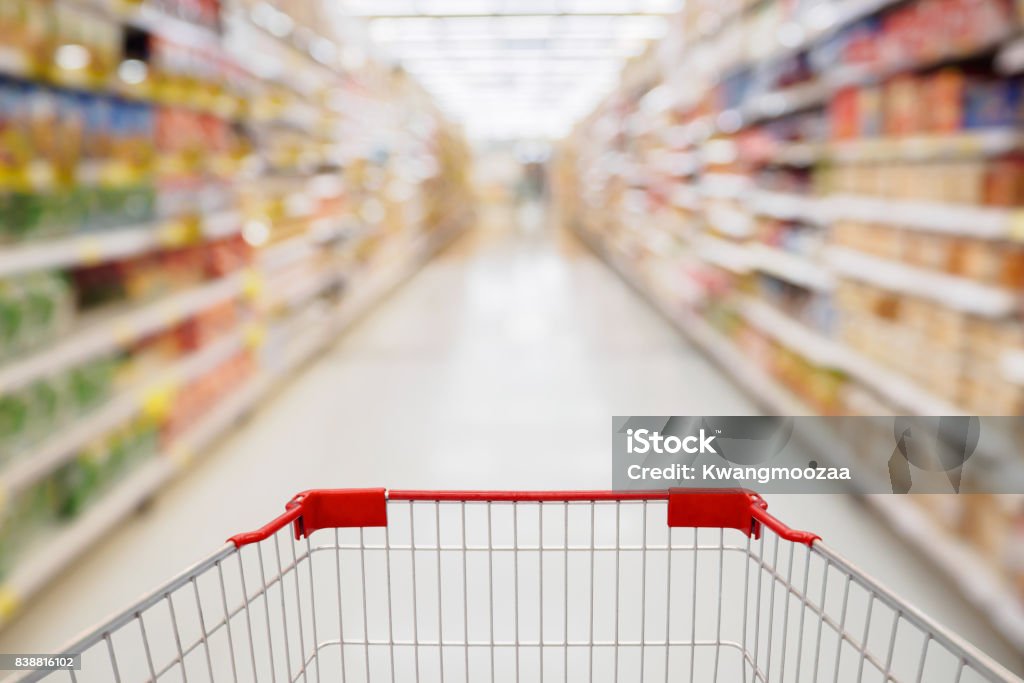 Shopping cart view in Supermarket aisle with product shelves abstract blur defocused background Supermarket Stock Photo