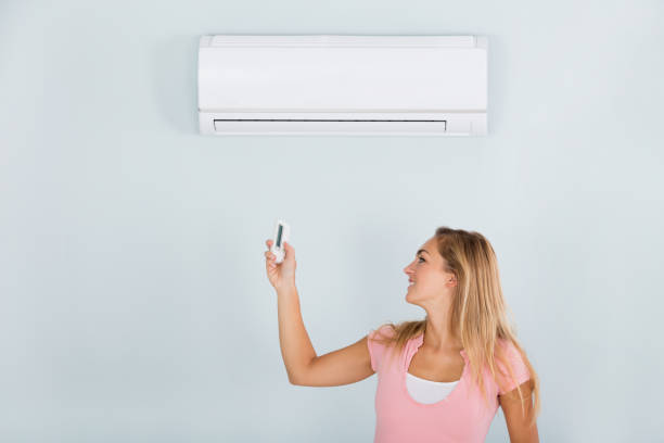 istock Woman Operating Air Conditioner With Remote 838829870