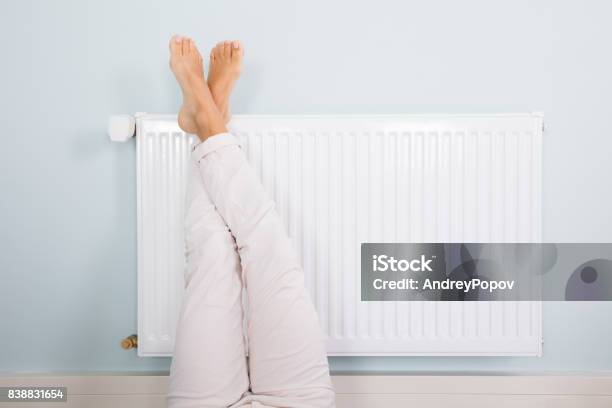 Mujer Calentando Sus Pies En Blanco Radiador Foto de stock y más banco de imágenes de Radiador - Radiador, Estufa eléctrica, Pie - Anatomía