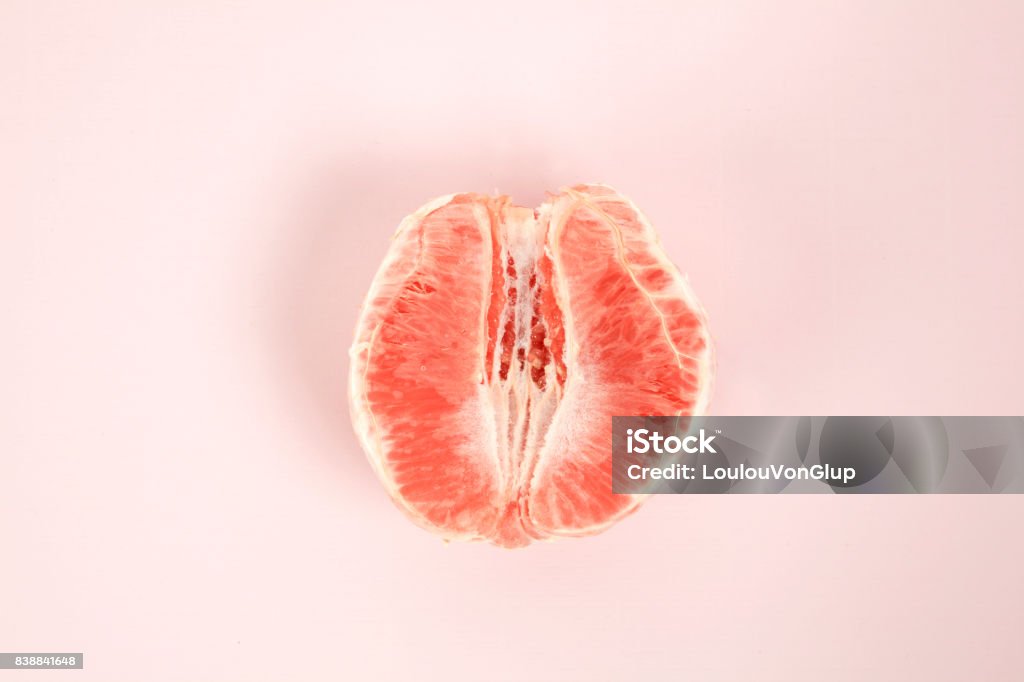 half peeled grapefruit a half peeled grapefruit on a pop colored background. Minimal color still life and quirky photography Grapefruit Stock Photo