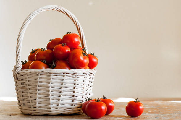 istock Red cherry tomatoes in a woven basket on a white background on wooden table 838845572