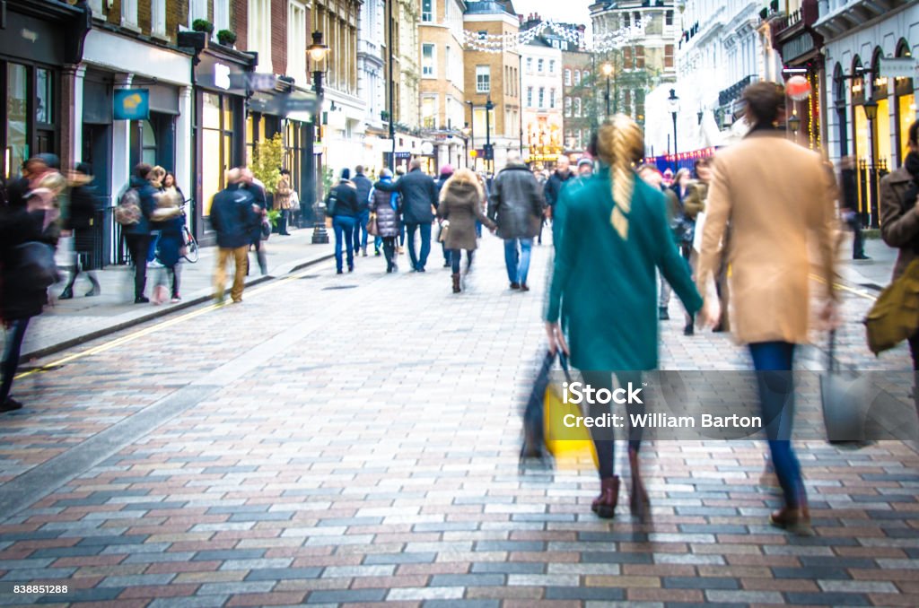 Shoppers walking down the high street holding hands and carrying shopping bags Blurred to show movement and no recognisable faces or logos. Retail Stock Photo