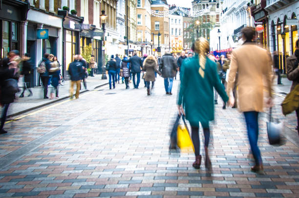 Shoppers walking down the high street holding hands and carrying shopping bags Blurred to show movement and no recognisable faces or logos. london fashion stock pictures, royalty-free photos & images