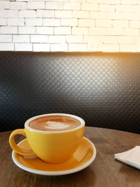 istock cup of latte coffee in yellow cup on wooden table 838853046