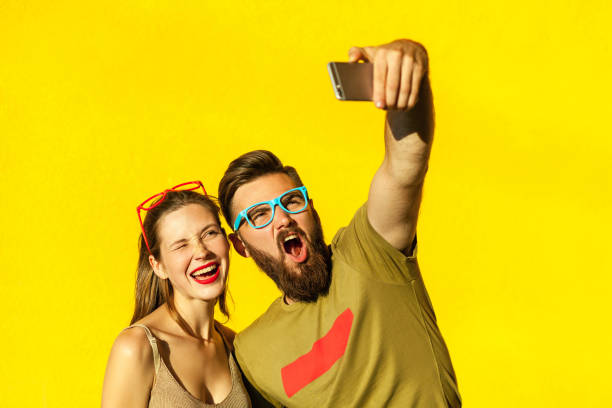 Hipsters couple macking selfie on yellow background