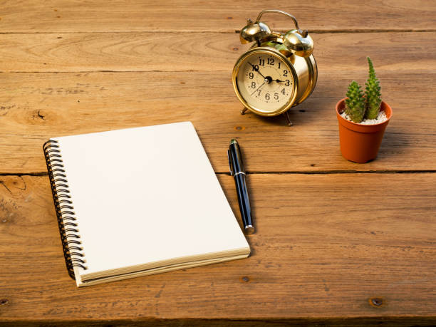 istock Blank notebook with vintage alarm clock and black pen and cactus on wood table 838856744