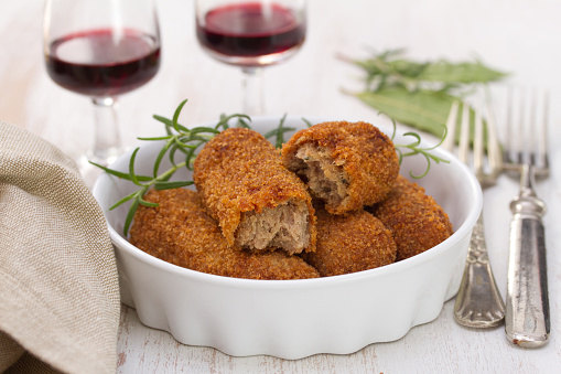 meat croquettes in dish and red wine on white background