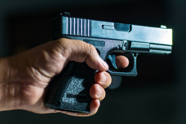 istock Man's hand holding a handgun on black 838859840