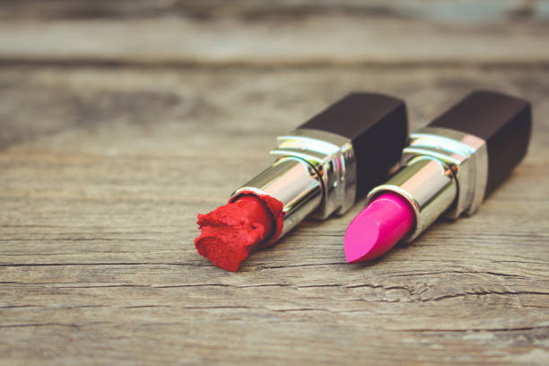 istock Broken red and new pink lipsticks on old wooden background. Toned image. 838874572