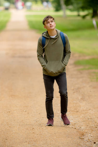 Teenage boy walking in a park on a summers afternoon