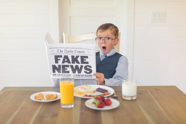 A Young Businessman Reading Fake News is Shocked A young buisnessman dressed in a business suit is sitting at the dining room table with a great American breakfast of eggs, bacon, toast and orange juice while he is reading the shocking version of fake news. Can the media be trusted anymore? fake news stock pictures, royalty-free photos & images