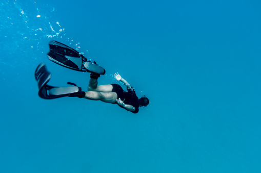 A DSLR Canon underwater photo of a Brazilian man enjoying his vacation at tropical island Fernando de Noronha, Brazil. He is free diving wearing snorkeling equipment in clear blue water at Sancho Beach (Praia do Sancho), which has been considered the most beautiful beach in the world.
