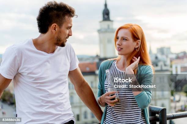 Couple Talking On A Rooftop Party Stock Photo - Download Image Now - 25-29 Years, Adult, Adults Only