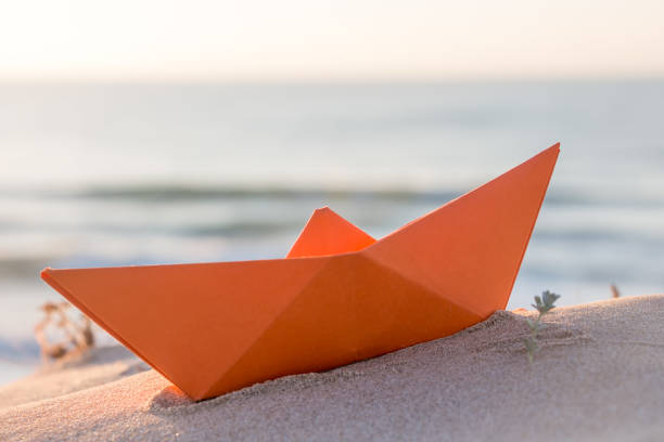 istock Orange paper boat on a beach 838902648