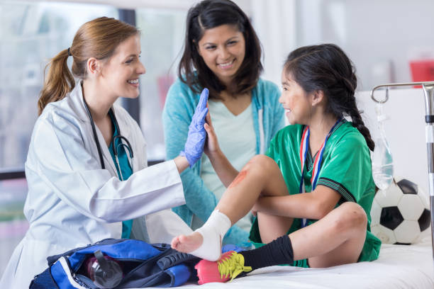 Emergency room doctor gives young patient a high five Emergency room doctor and an elementary age female patient high five one another. The girl has a sprained ankle. The girl's mom is smiling in the background. sprain stock pictures, royalty-free photos & images