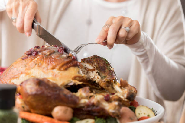 Senior woman carves turkey at Thanksgiving