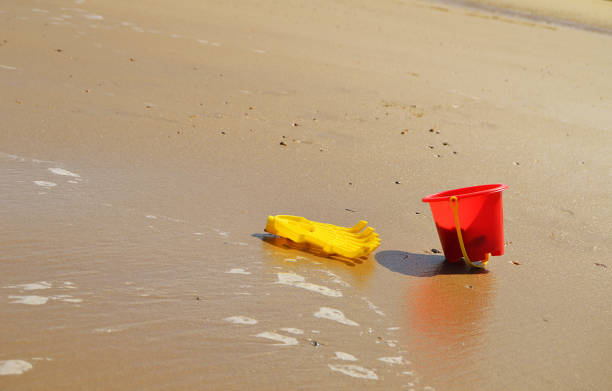 istock A yellow plastic rake and a red plastic bucket or sand pail on a sandy beach 838917558