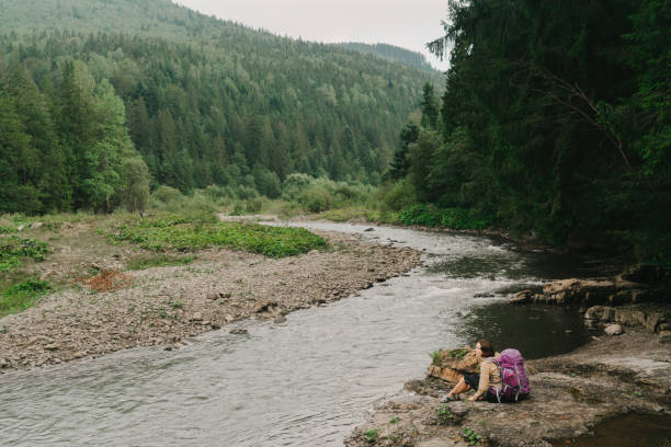 istock Woman with backpack  sitting near  the river 838927916