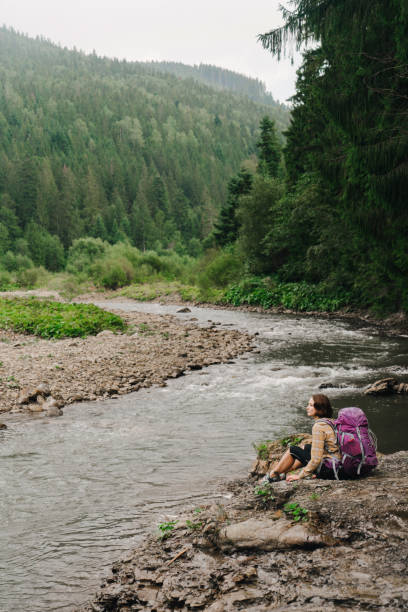 istock Woman with backpack  sitting near  the river 838927924