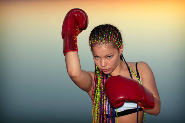 Portrait of a girl with red boxing gloves on background of the sundown