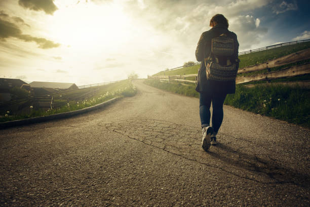 Woman is walking on the road at sunset