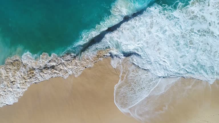 Aerial drone footage of ocean waves reaching shore.