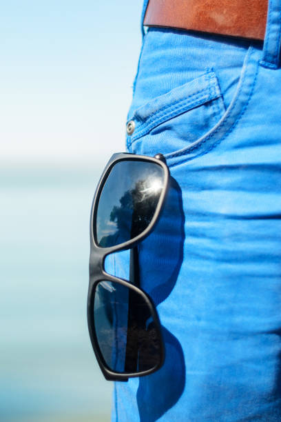 istock Sunglasses hanging out of front pocket on blue jeans 838974684