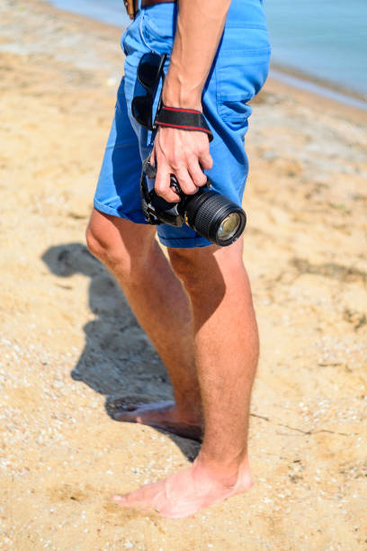 istock DSLR camera in hand in sea beach background 838974720