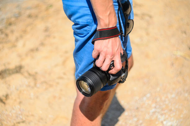 istock DSLR camera in hand in sea beach background 838974730
