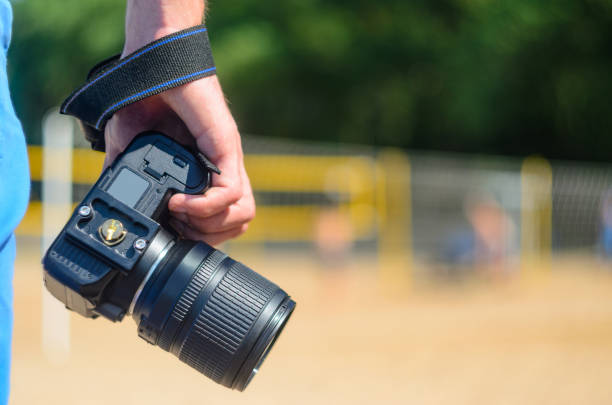 istock DSLR camera in hand in sea beach background 838974742
