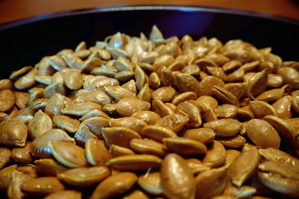istock Macro closeup pumpkin seeds on black dish brown skin 838978198