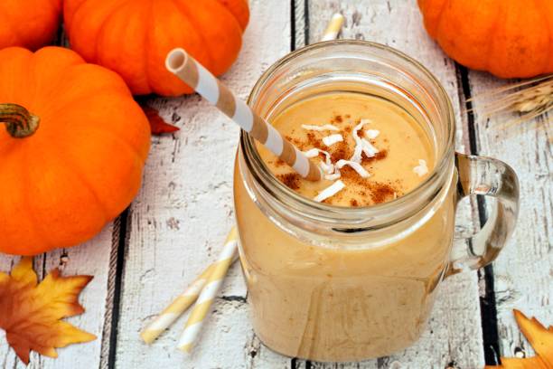 istock Pumpkin smoothie in a mason jar, scene on white wood 838978628
