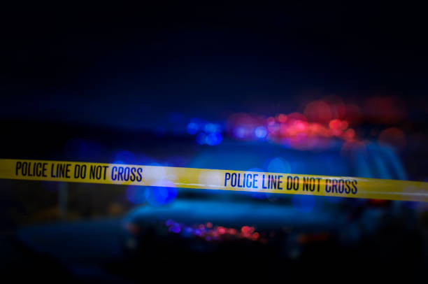 Police Crime Scene A stock photo of a Police Line "Do Not Cross" caution tape with a defocused police car with sirens flashing red and blue. police vehicle lighting stock pictures, royalty-free photos & images
