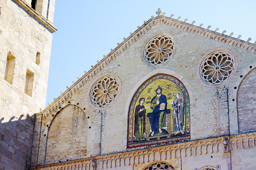 Spoleto, Umbria, Italy: The beautiful facade (with gold mosaic) of Santa Maria Assunta Cathedral in Spoleto dating from the 12th century, with a pale blue sky background. Spoleto is in Perugia Province.
