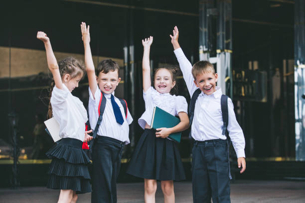 piękne dzieci w wieku szkolnym aktywne i szczęśliwe na tle szkoły w mundurkach - happy ending zdjęcia i obrazy z banku zdjęć