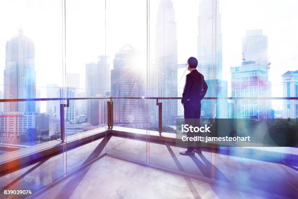 Young Businessman Looking Out The City In The Office Morning Scene Stock Photo - Download Image Now