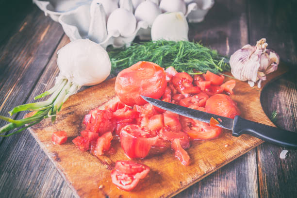 istock Omelette preparation with cut tomatoes, dill, onion, eggs and knife. Toned image. 839044740