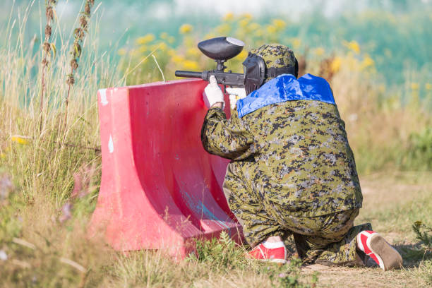 paintball sport player in protective uniform and mask playing and shooting with gun outdoors. - paintballing violence exercising sport imagens e fotografias de stock
