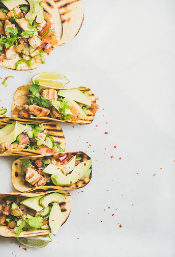 Healthy corn tortillas with grilled chicken fillet, avocado, fresh salsa, limes over light grey marble table background, top view, copy space. Gluten-free, allergy-friendly, weight loss concept