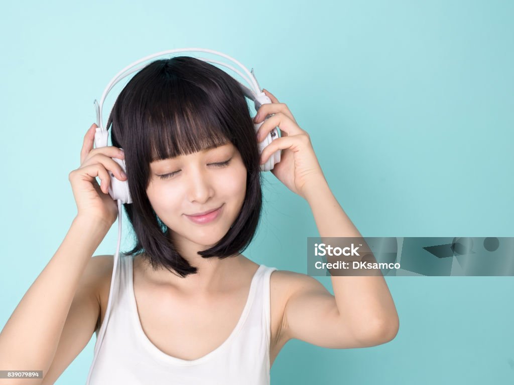 Asiatische Frau genießen Sie Musik mit Kopfhörer, isoliert auf blauem Hintergrund - Lizenzfrei Asien Stock-Foto