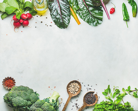 Raw fruits and vegetables varied vegan food on monochrome green table full frame background