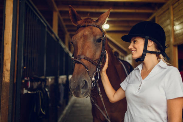 istock Woman in a barn stroking her horse 839100364