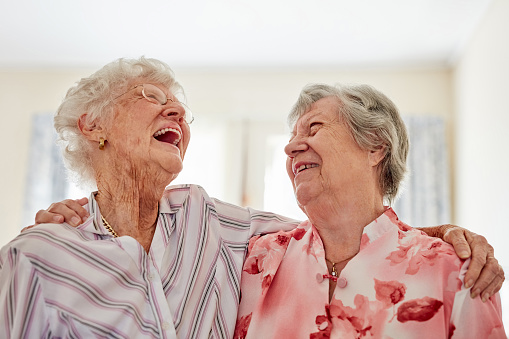 Shot of two happy elderly women embracing each other at home