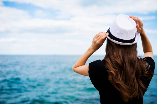 Woman in hat near sea. Back view
